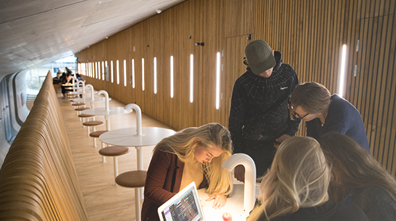 Fire elever står rundt om et gruppebord